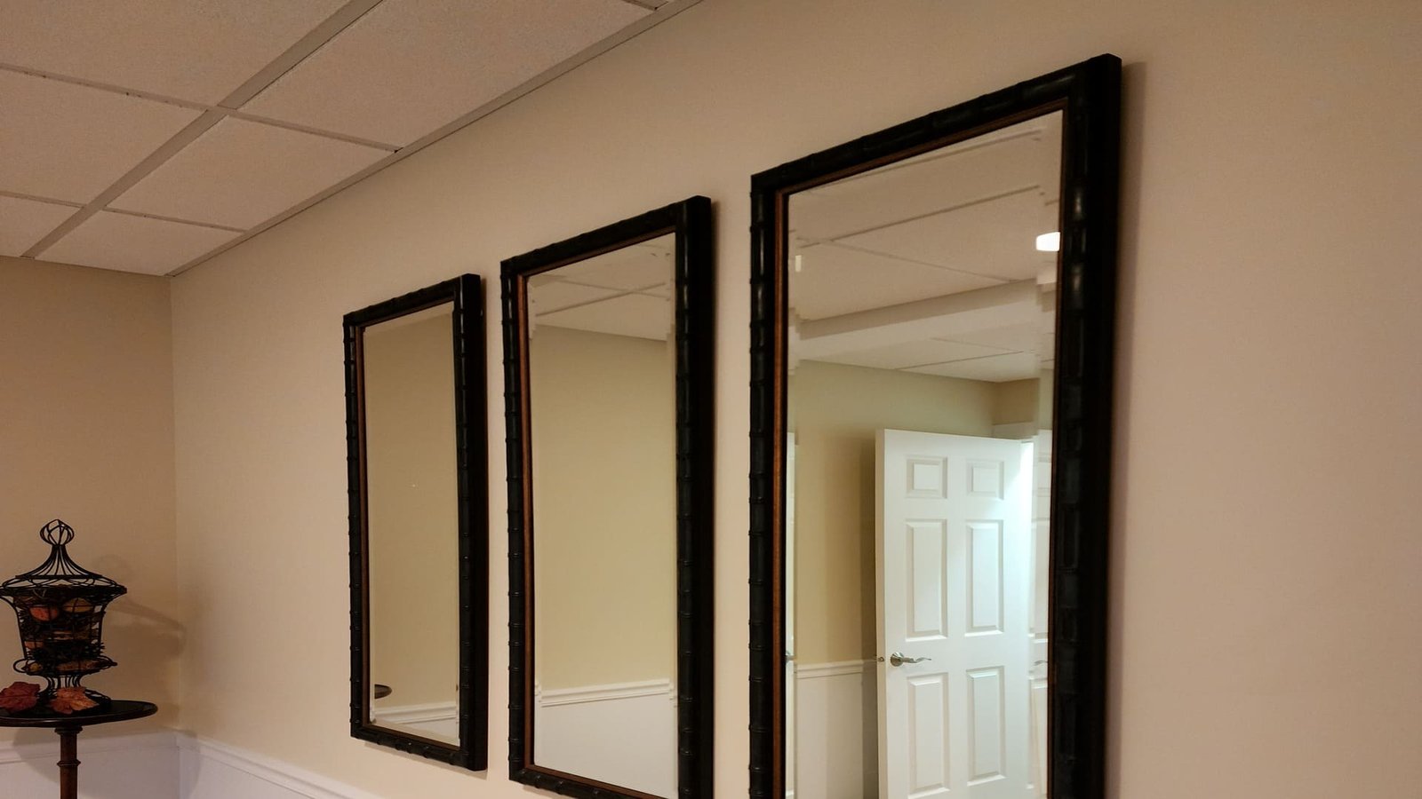 Three matching black framed mirrors hung in a hallway
