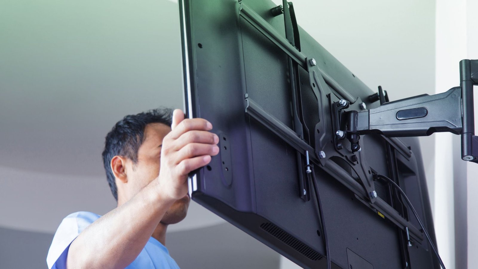 Installer lifting a television onto a wall bracket